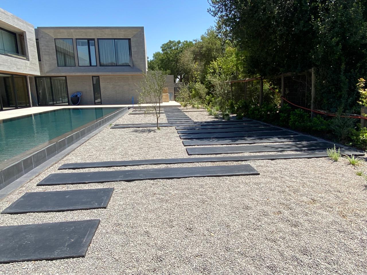 Jardín residencial con piscina y caminos de piedra