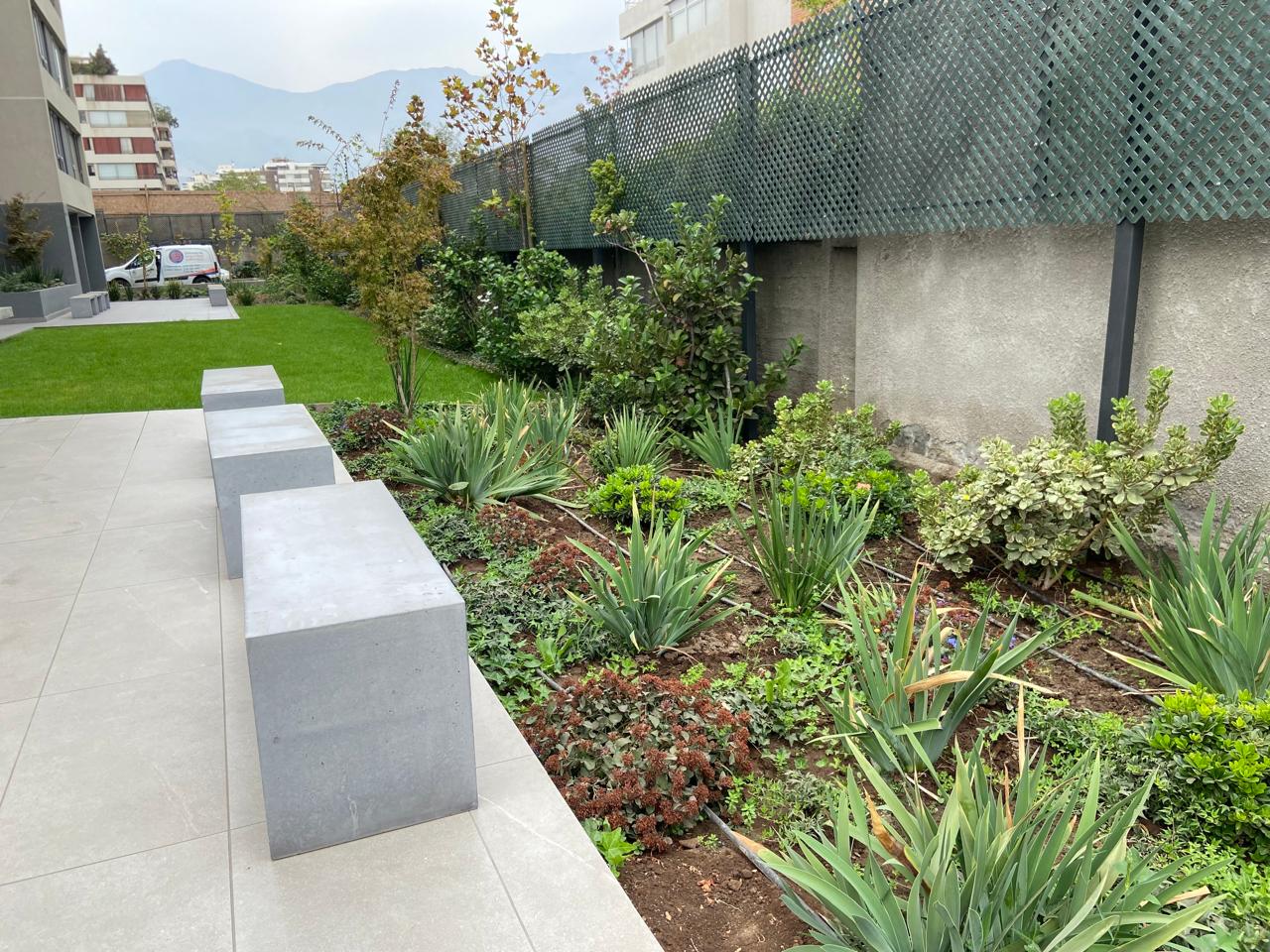 Jardín con bancas de concreto y vegetación nativa